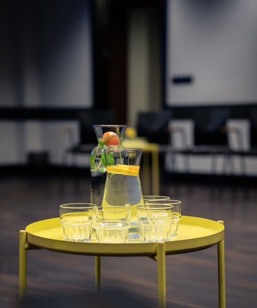 Two carafes of lemonade and empty glasses on a yellow table
